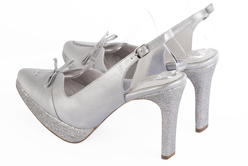 Light silver women's open back shoes, with a knot. Tapered toe. Very high slim heel with a platform at the front. Rear view - Florence KOOIJMAN